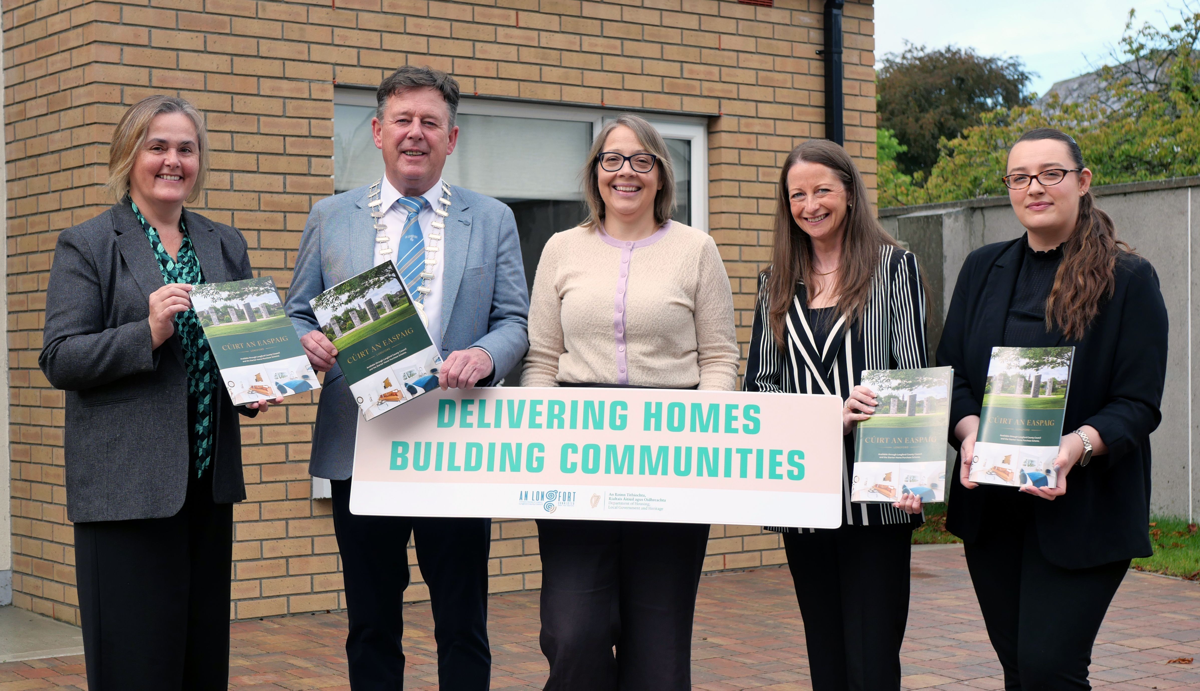 Five people standing outside new housing development